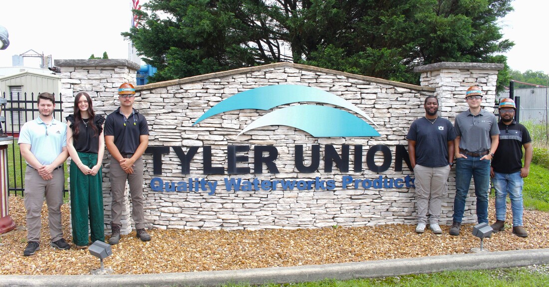 Tyler Union's interns are pictured standing and smiling in front of a stone Tyler Union site in front of the company's facility.